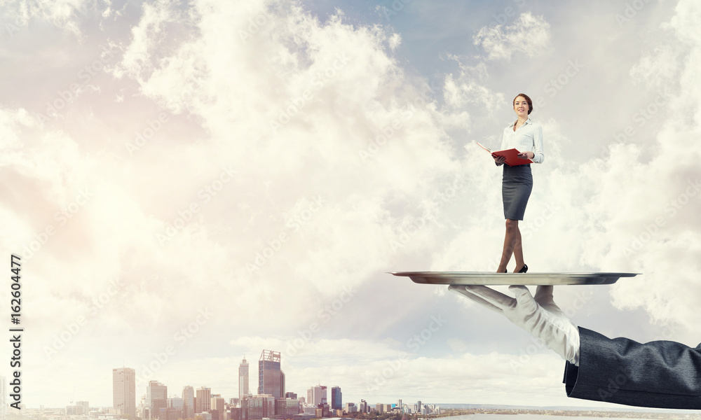 Attractive businesswoman on metal tray with red book in hands against cityscape background Attractive businesswoman on metal tray with red book in hands against cityscape background
