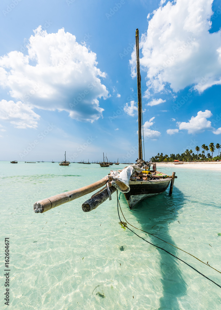 wooden boat anchored on the African shore in clear ocean water - obrazy, fototapety, plakaty 