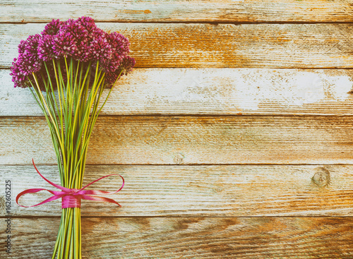 bouquet of beautiful purple allium flowers tied with a purple ribbon on wooden retro background with space for text. Flat lay  top view