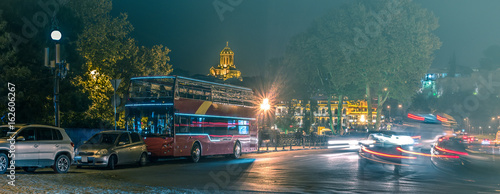 red sightseeing bus on Tbilisi night road with cars © Ievgen Skrypko