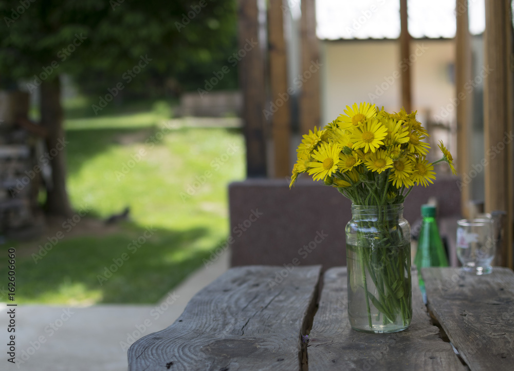Yellow daisy flowers in vase on wooden table