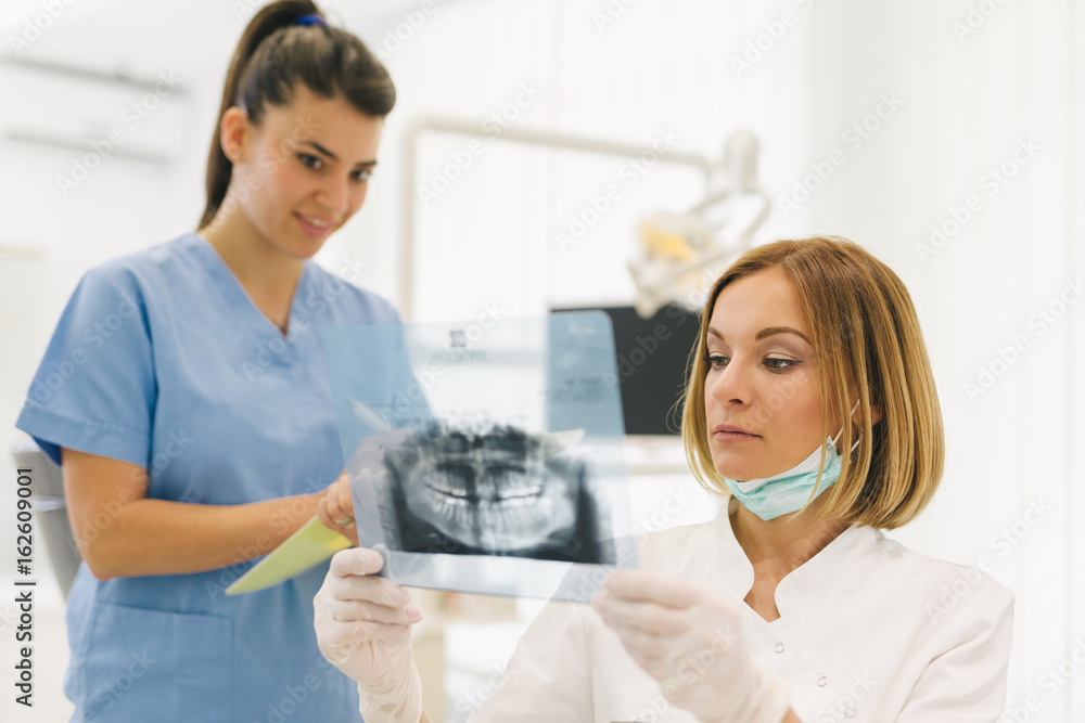 Fototapeta premium woman dentist with her assistant examine dental x-ray