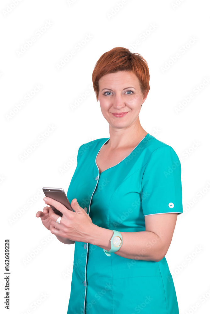 Pretty red-hair smiling woman nurse, cosmetologist, doctor, with smartphone mobile phone in her hands, isolated on white background, looking at the camera Pretty red-hair smiling woman nurse, cosmetologist, doctor, with smartphone mobile phone in her hands, isolated on white background, looking at the camera
