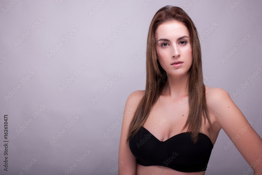 Gorgeous woman in bra with natural make up on gray background in studio photo. Beauty and fashion. Gorgeous woman in bra with natural make up on gray background in studio photo. Beauty and fashion.