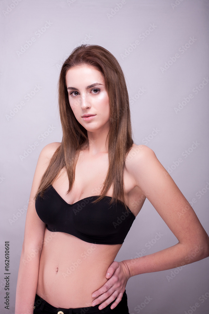 Fototapeta premium Beautiful woman in bra with natural make up on gray background in studio photo. Beauty and fashion.