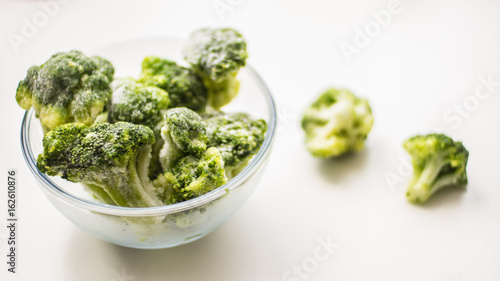 Frosen broccoli in a glass bowl on a wooden surface
