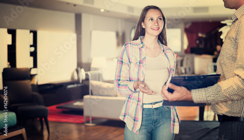 Salesman offering furniture variants to woman in salon