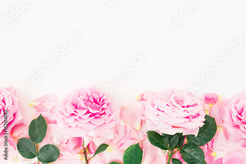 Floral frame of pink roses and petals on white background. Floral composition. Flat lay  top view