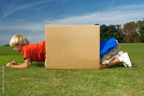 Valokuva two boys crawling into box