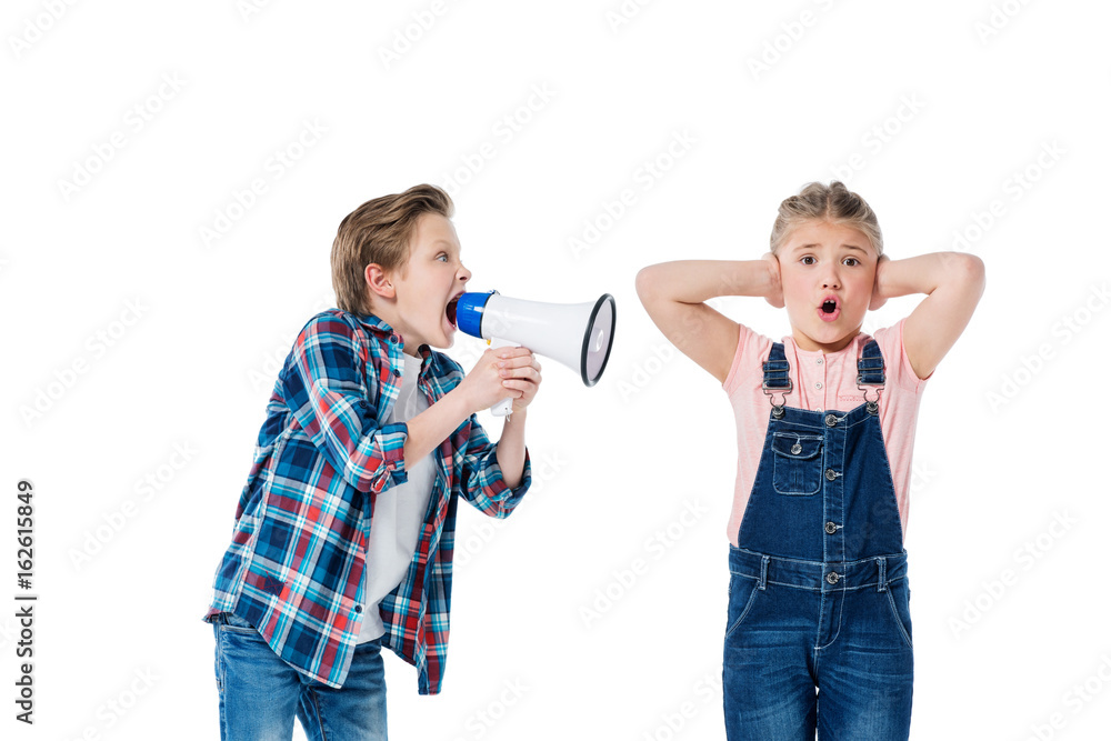 Boy holding megaphone and screaming at littke girl closing ears Boy holding megaphone and screaming at littke girl closing ears
