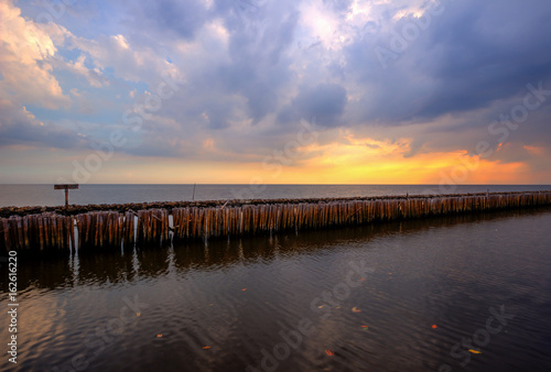 Evening sky rows of bamboo sticks in the sea and cement bridge near Matchanu Shrine Phanthai Norasing Mueang Samut Sakhon District Samut Sakhon Thailand.