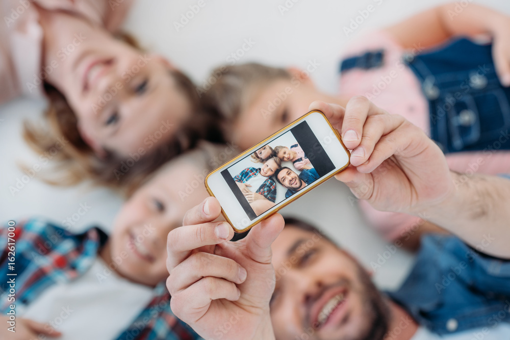 happy caucasian family smiling while taking selfie on smartphone