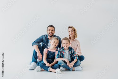 smiling family looking at camera while sitting together on the floor