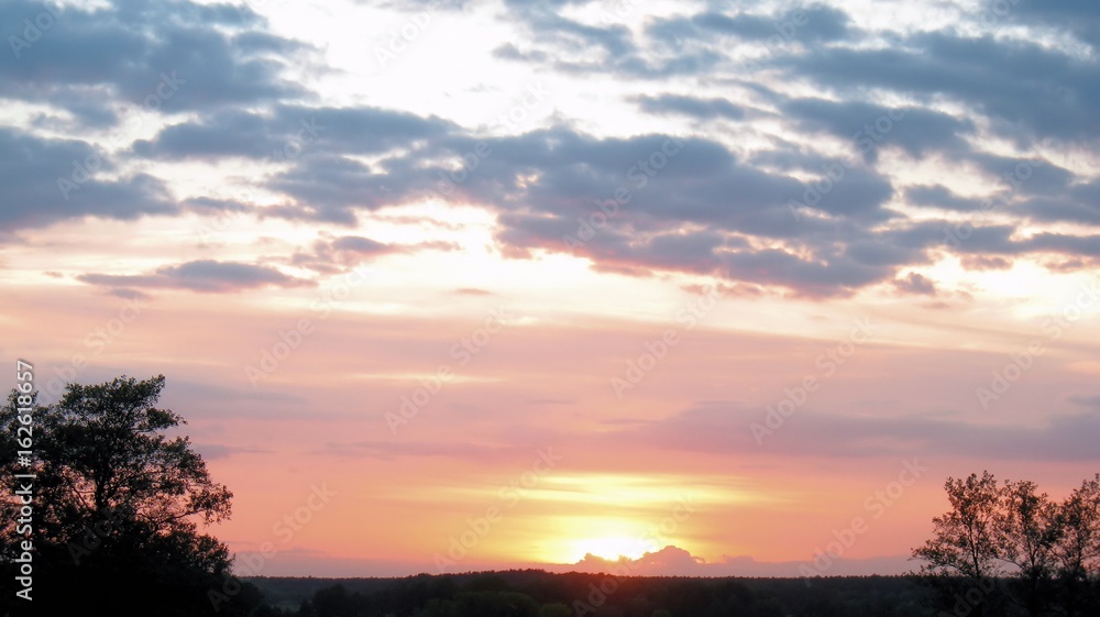 Orangeroter Sonnenuntergang über Feld mit Wolken