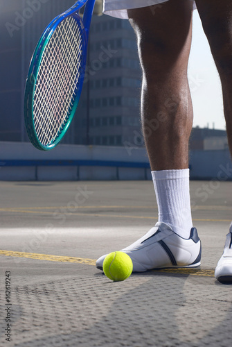 Tennis player with ball on rooftop court