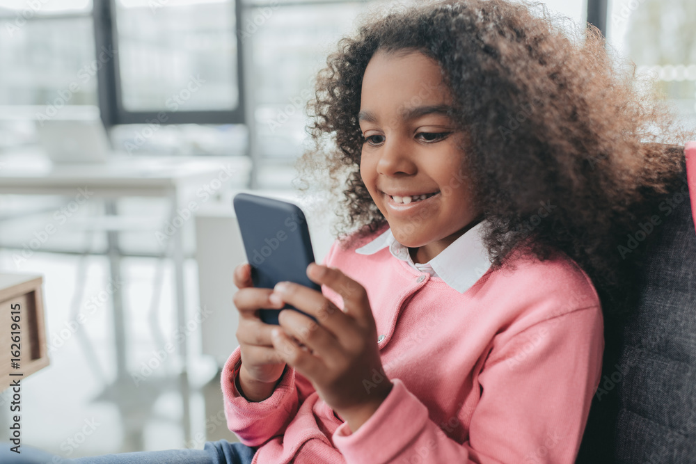 little happy african american girl with curly hair using smartphone little happy african american girl with curly hair using smartphone