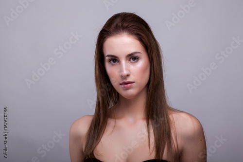 Gorgeous woman in bra with natural make up on gray background in studio photo. Beauty and fashion.