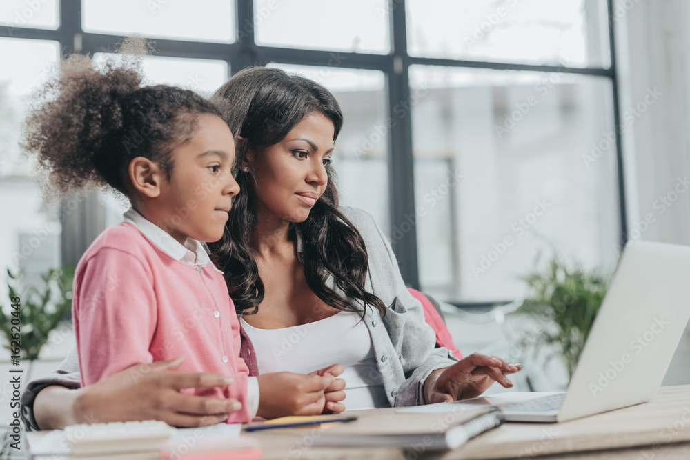 Φωτογραφία businesswoman typing on laptop with daughter near by, work and life balance conc