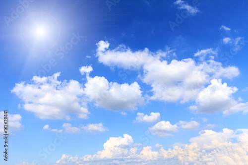 Blue sky background with white clouds, rain clouds and sunshine on sunny summer or spring day.