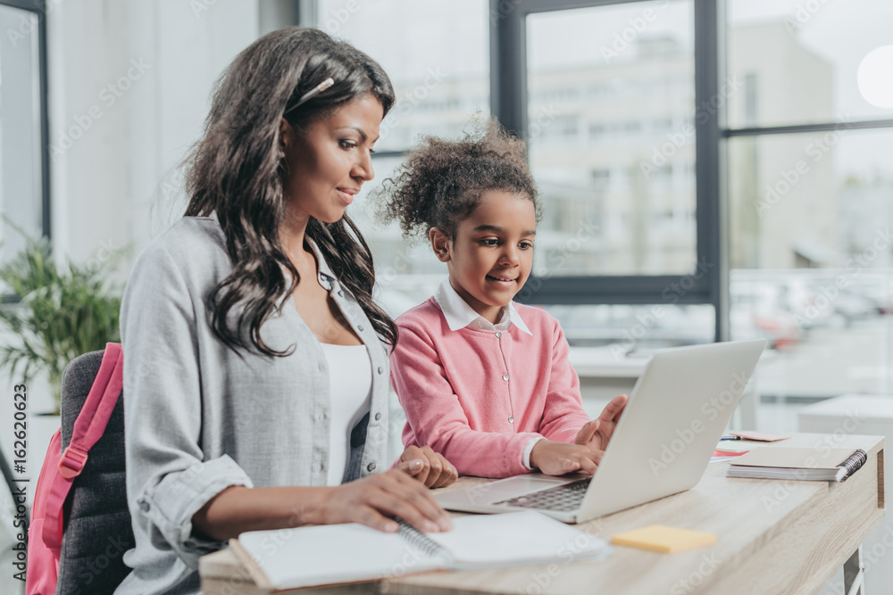 little daughter helping mother working on laptop at business office, work and life balance concept little daughter helping mother working on laptop at business office, work and life balance concept