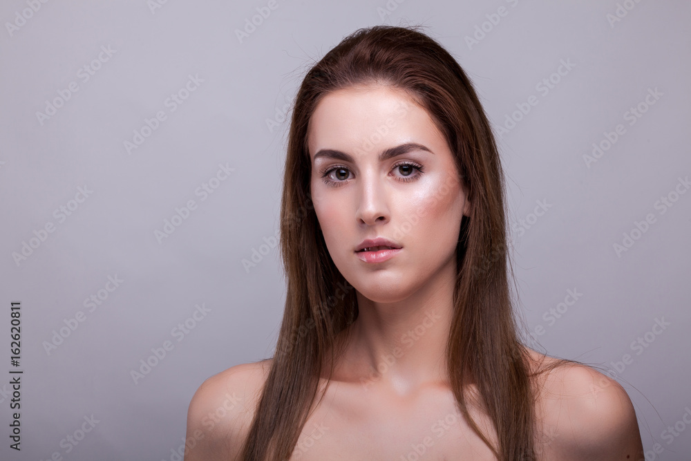 Portrait of beautiful woman with clean face on gray background in studio photo. Beauty and fashion. Portrait of beautiful woman with clean face on gray background in studio photo. Beauty and fashion.