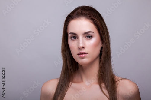 Portrait of beautiful woman with clean face on gray background in studio photo. Beauty and fashion.