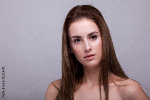 Beauty portrait of woman with no makeup on gray background in studio photo. Beauty and fashion.