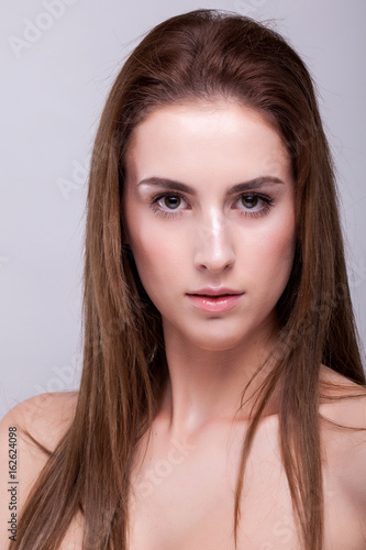 Expressive woman with perfect skin and natural make up on gray background in studio photo. Beauty and fashion.