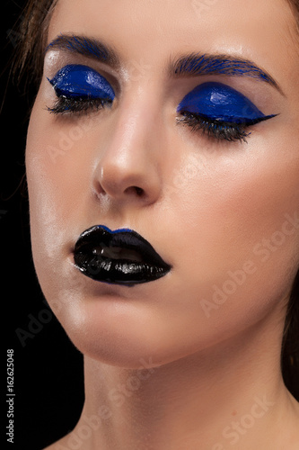 Gorgeous woman wearing blue make up with black lips in studio photo. Beauty and fashion. Cosmetic and creative artistic make up