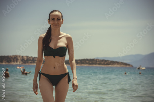 The girl in the green swimsuit out of the blue sea. Travel concept and vacation in the resort