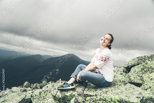 Young pretty woman in national ukrainian dress on the peak of the carpathian mountains