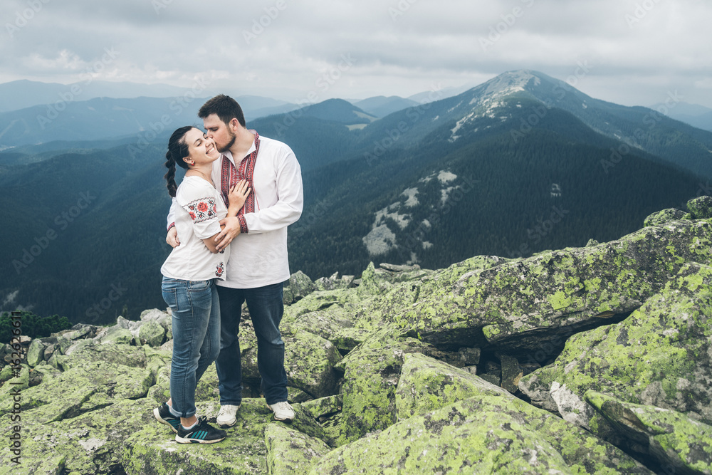 man and woman kissing each other on the top of the mountain