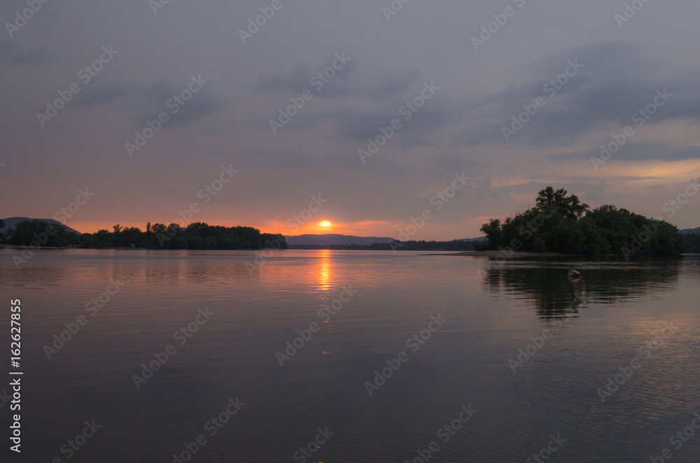 sunset view from the shore of the river. summer sunset on beach, reflection of sun