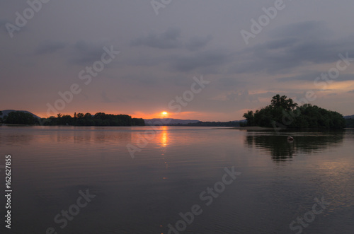 sunset view from the shore of the river. summer sunset on beach, reflection of sun © pellephoto