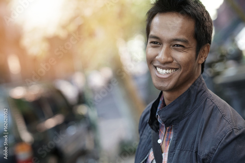 Smiling mixed-raced guy standing in the street