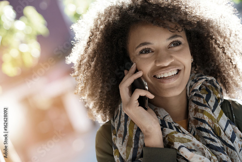 Smiling mixed raced girl talking on smartphone in the street