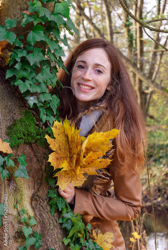 Beautiful young lady in autumn landscape - Goldener Herbst - Junge rotharige Frau lachend im Wald mit gelben Blättern  photo