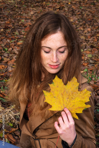 Beautiful young lady in autumn landscape - Goldener Herbst - Junge rotharige Frau lächelnd im Wald mit gelben Blättern  photo