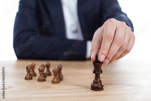 cropped view of businessman holding chess figure in hand