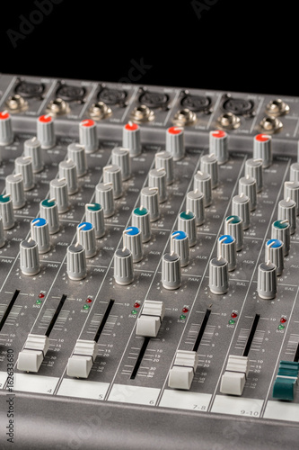 Audio mixing console with sliders and knobs on the channels.