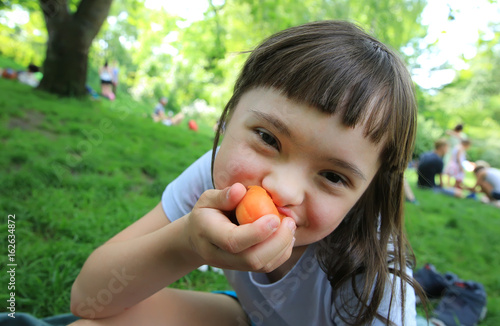 Young girl eating apricot in the park