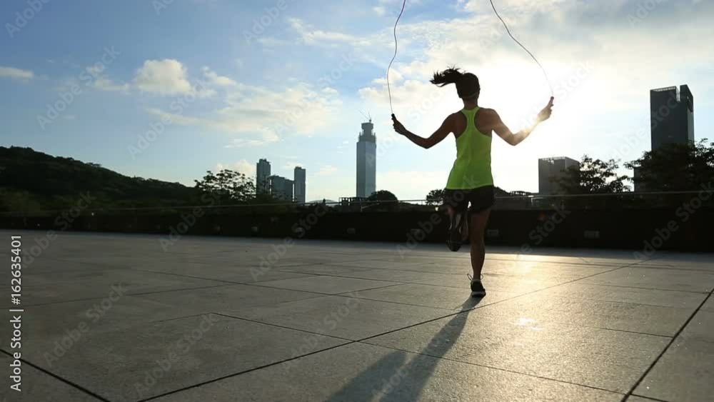 young fitness woman jumping rope on sunrise city building roof young fitness woman jumping rope on sunrise city building roof