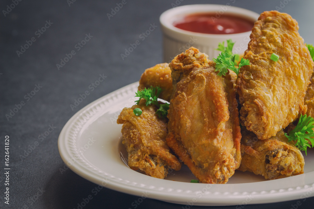 Fried chicken wings on white plate served with barbecue dipping sauce. Homemade fried chicken delicious and crispy. Close up fried chicken and chili sauce or tomato sauce (ketchup) ready to served Fried chicken wings on white plate served with barbecue dipping sauce. Homemade fried chicken delicious and crispy. Close up fried chicken and chili sauce or tomato sauce (ketchup) ready to served