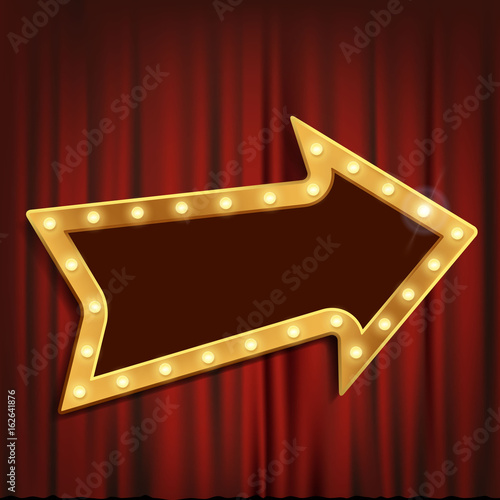 Golden arrow with light bulbs on the red theatrical curtain.