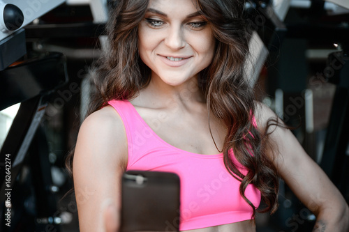 Fitness girl with a beautiful smile posing and exercise in the gym.