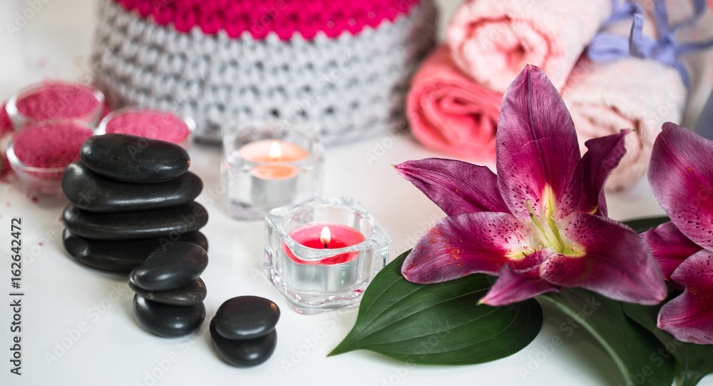 Nature products Spa and wellness setting with flowers, towels, stones and candle Nature products Spa and wellness setting with flowers, towels, stones and candle
