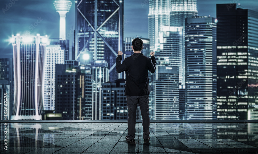 Back view of excited businessman with arms up , blurred morden city skyline . Back view of excited businessman with arms up , blurred morden city skyline .