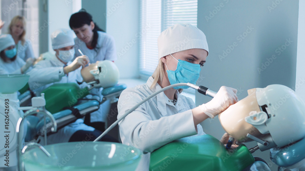 Students practicing dentistry on medical dummies in a teaching facility