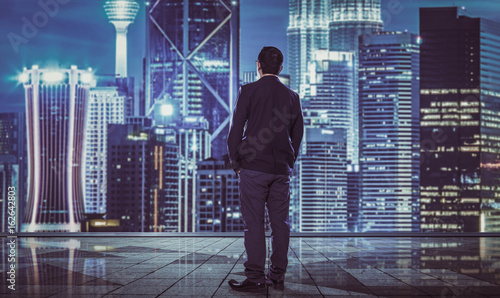 Rear view of indecisive businessman with blurred morden city skyline . © jamesteohart