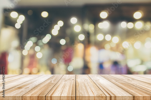 Empty wooden table top with blurred modern shopping mall background. Vintage color tone.